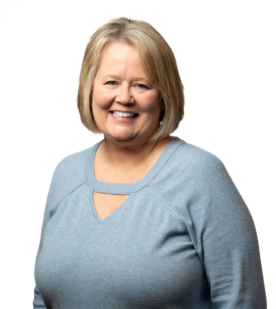 Woman with blonde hair, wearing a blue sweater, smiling.