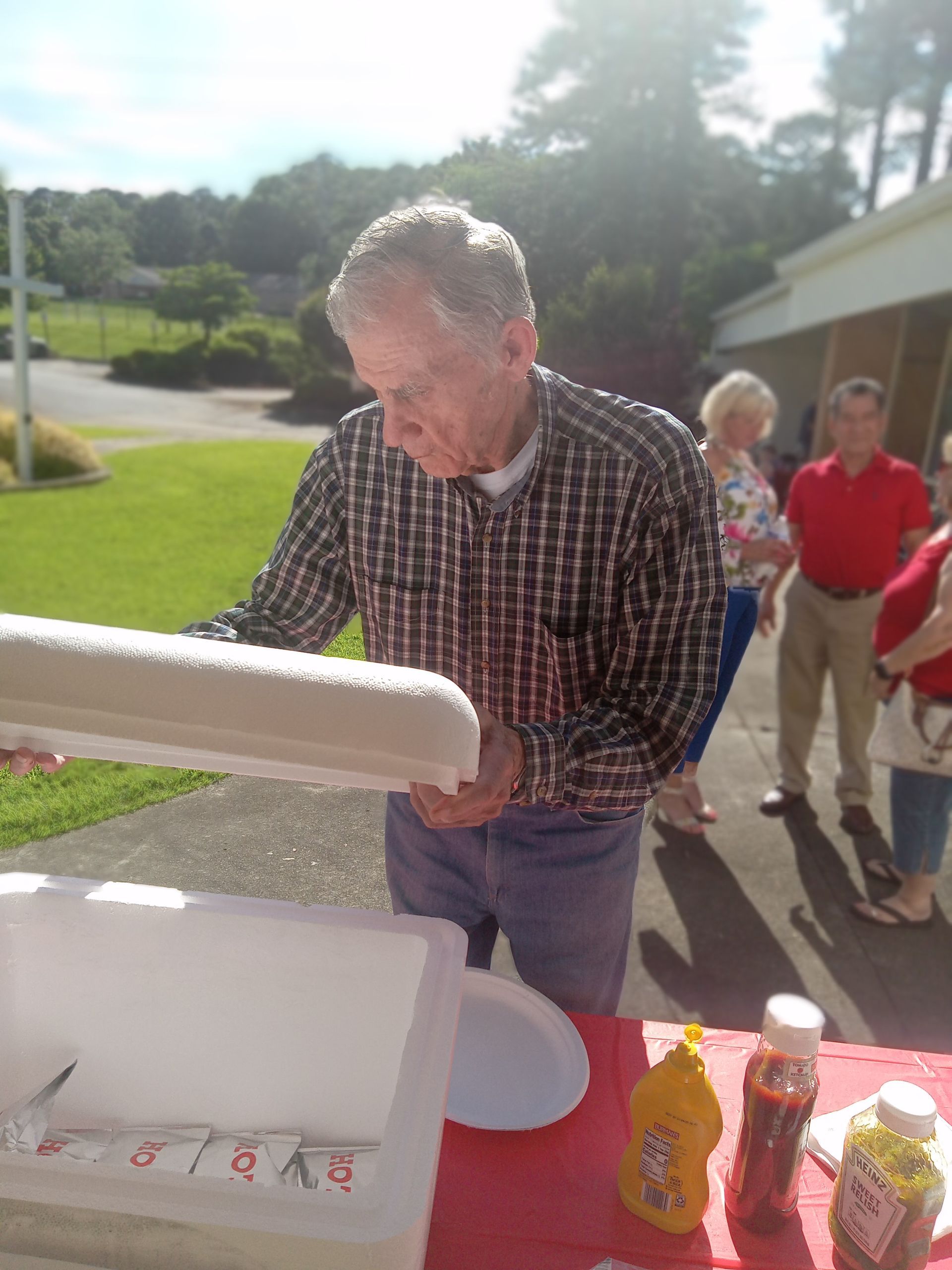 A man in a plaid shirt is opening a styrofoam container