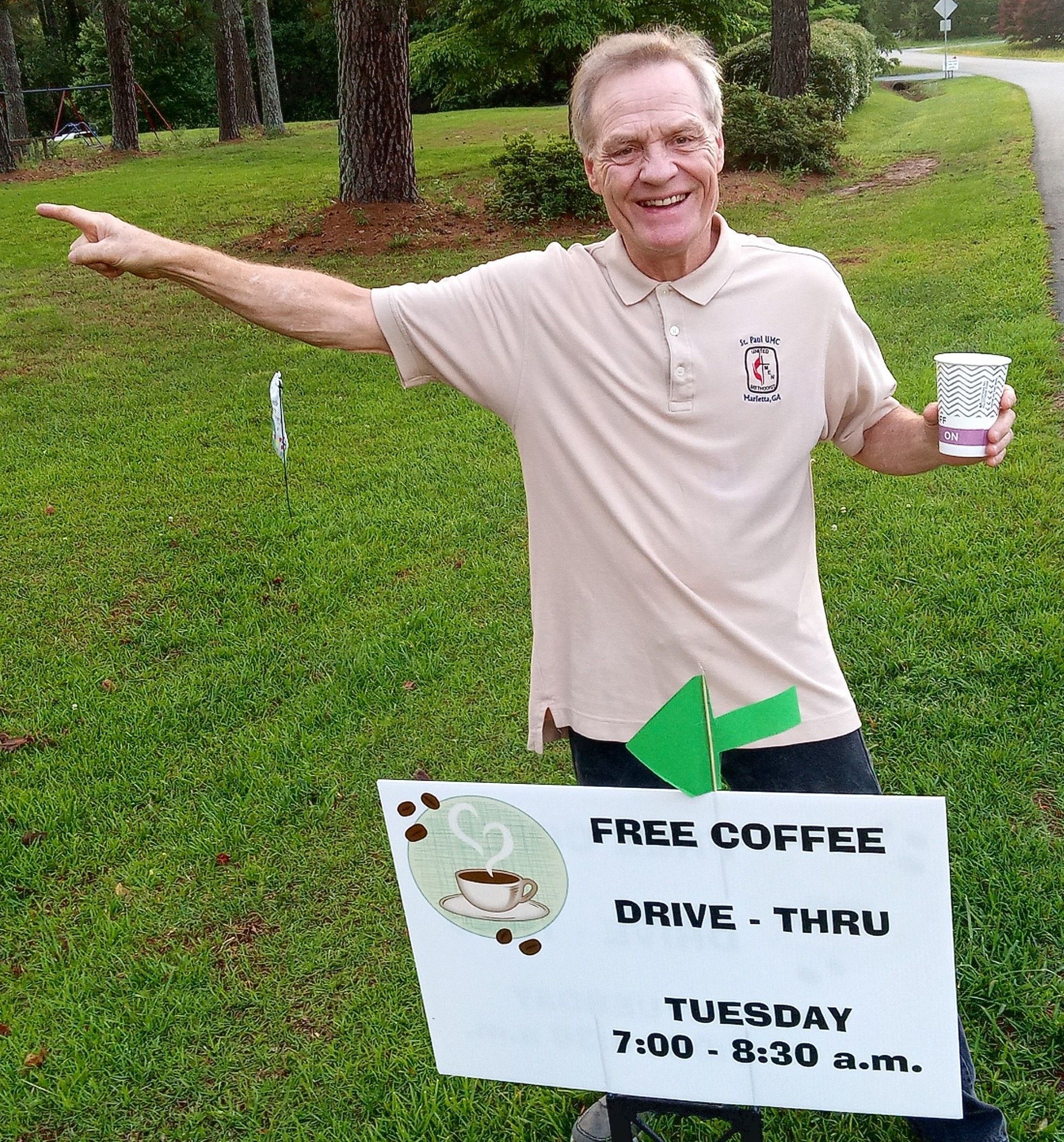 A man holding a cup of coffee and a sign that says free coffee drive thru