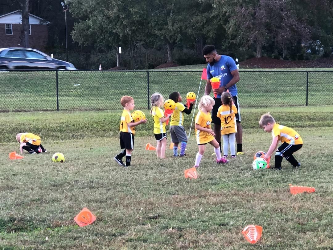 A group of young children are playing soccer on a field.