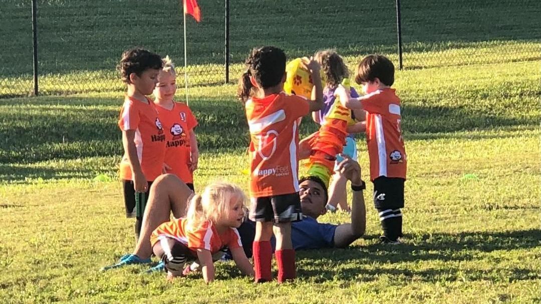 A group of young children are playing soccer on a field.