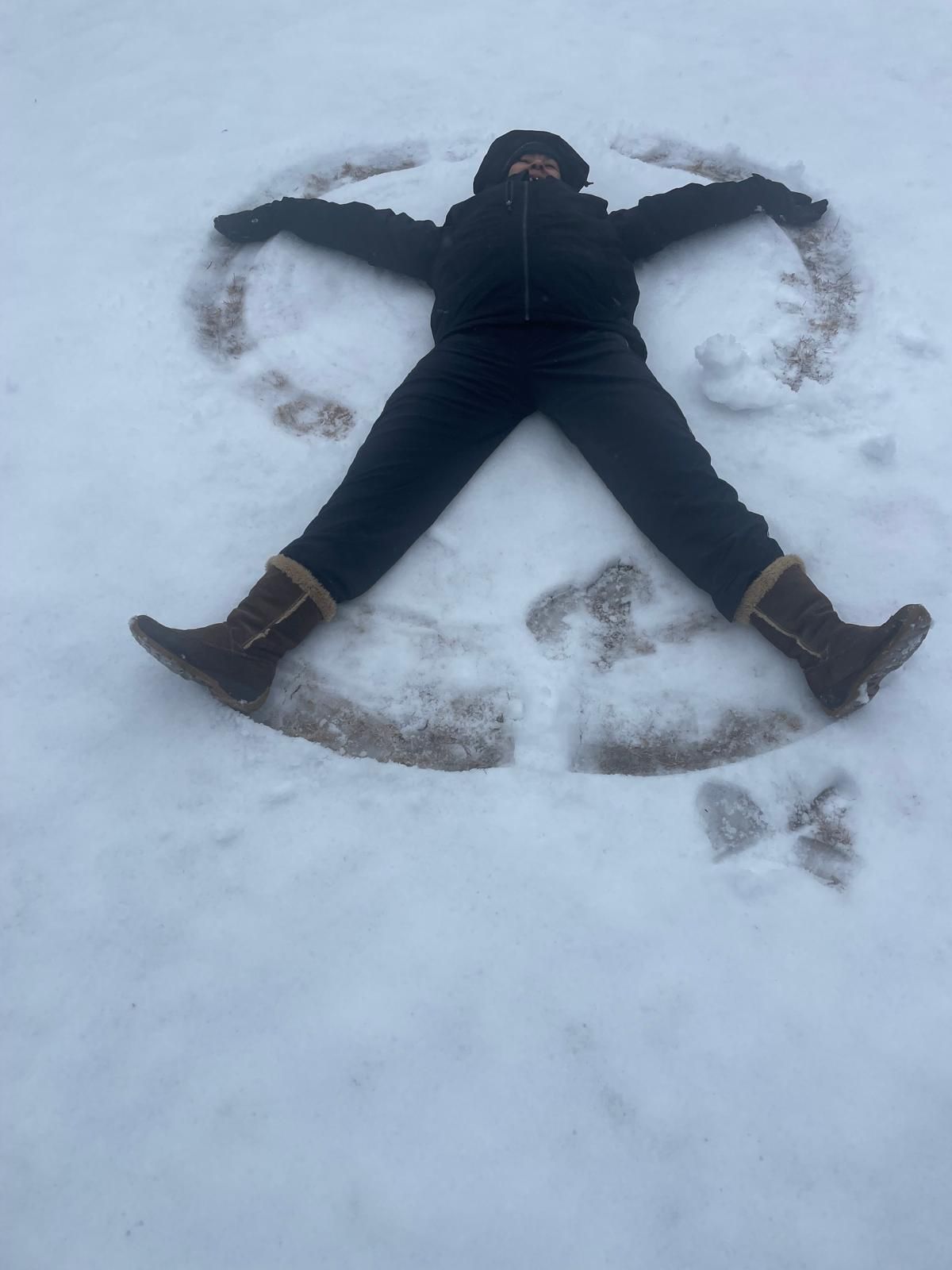 A person is laying in the snow making a snow angel