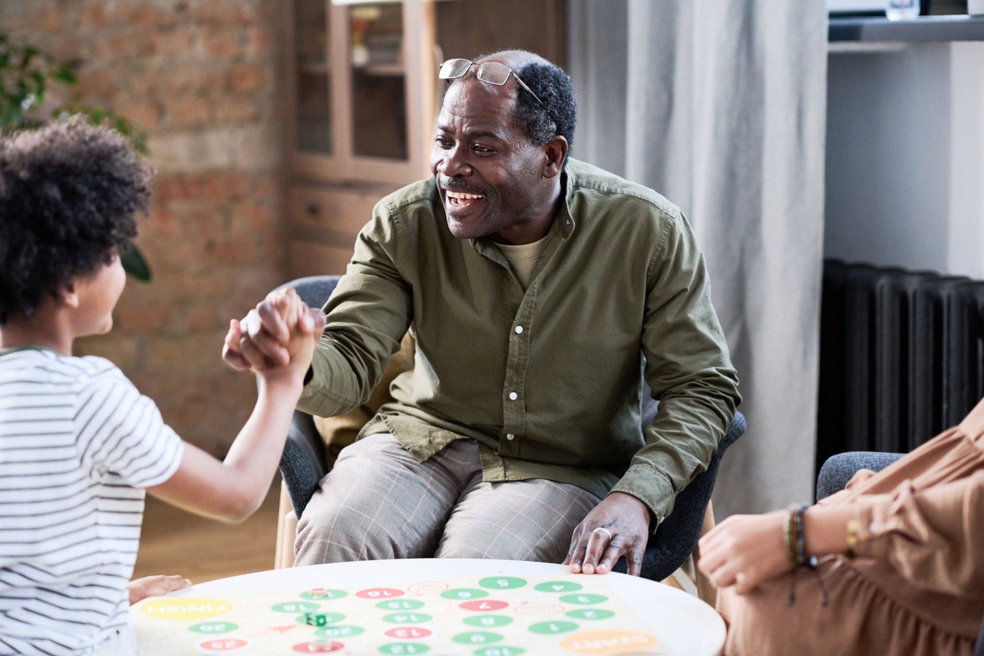 elderly black man playing board game with grandson