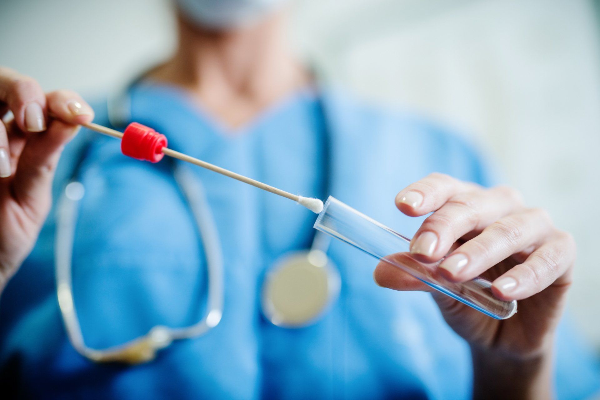 closeup of nurse inserting medical swab into test tube
