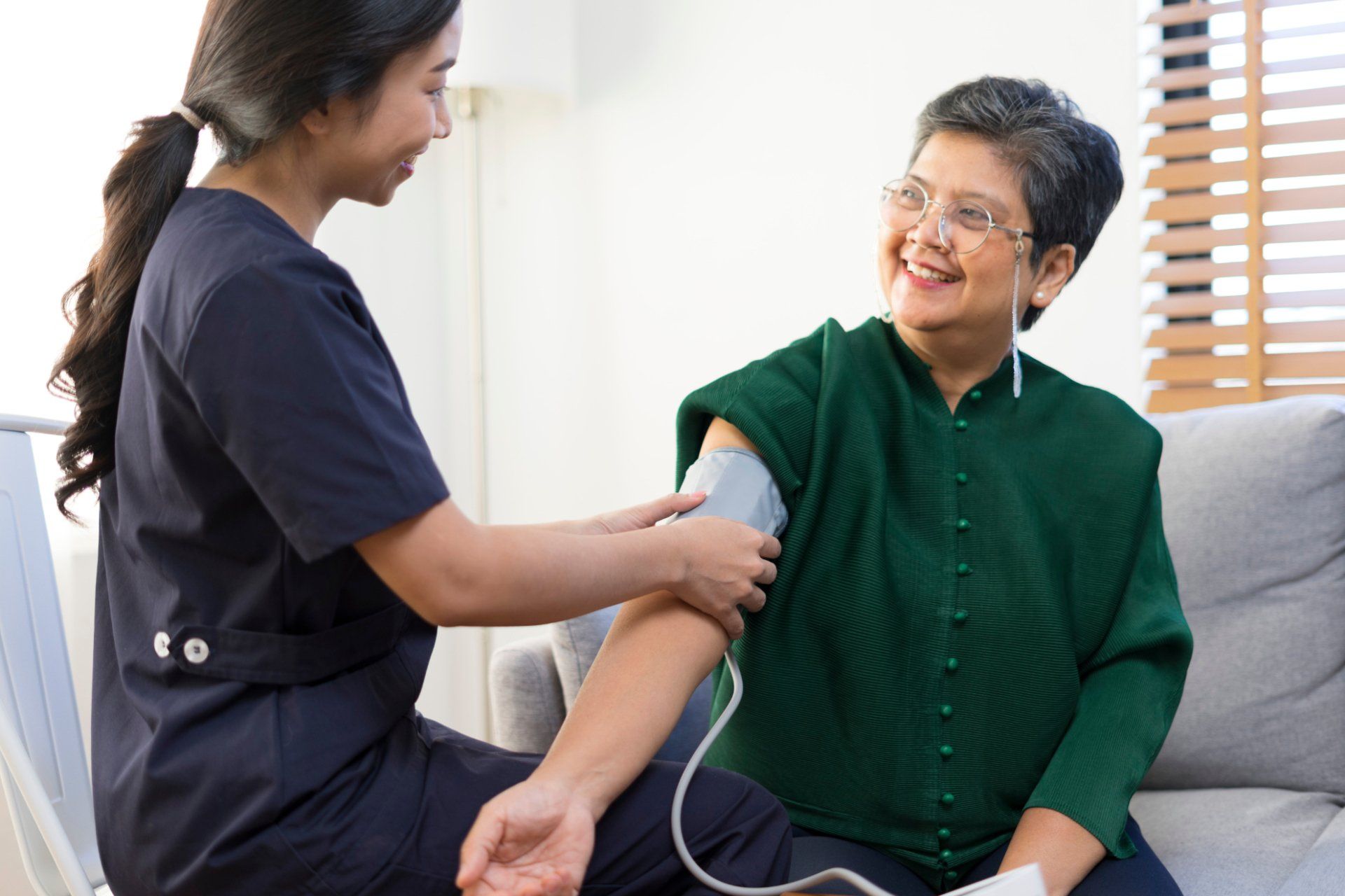 young nurse using blood pressure cuff on senior asian woman
