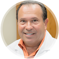 Smiling man in a white coat with orange shirt, posed in a circular portrait