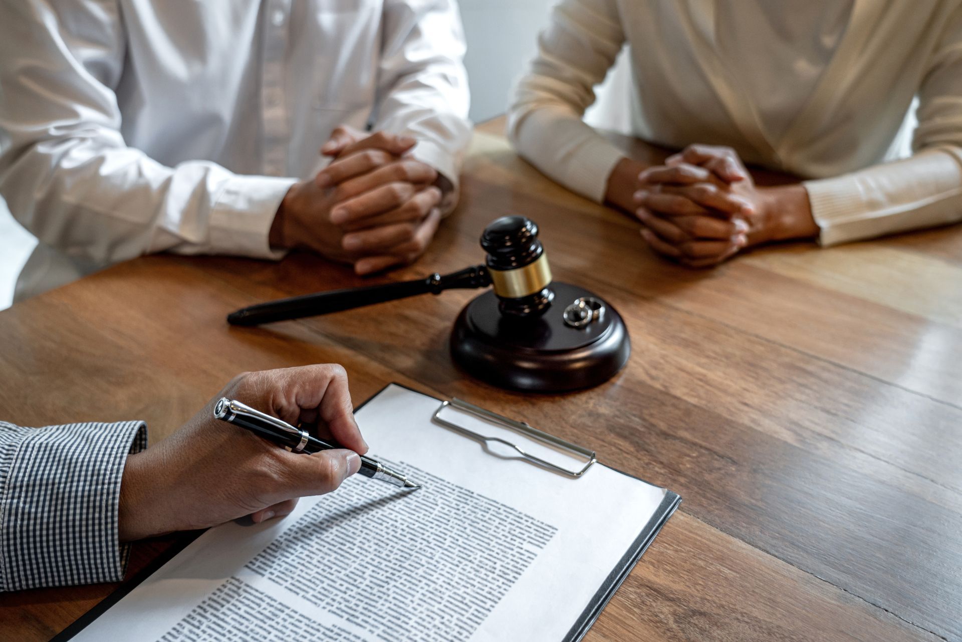 Lawyer taking notes as a couple meets with a judge’s gavel on a wooden table