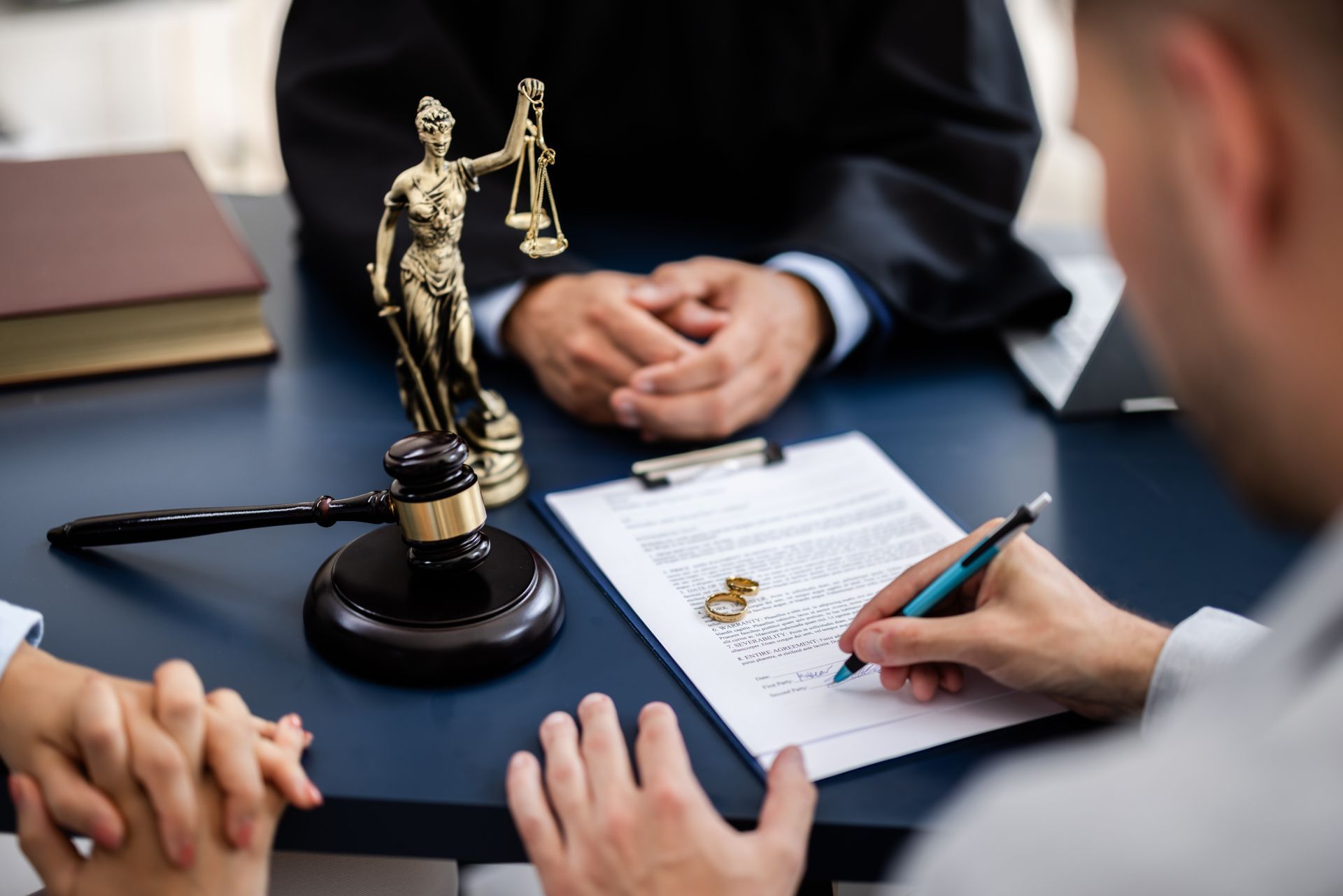 Lawyer and client discussing documents at a desk with a justice statue and gavel