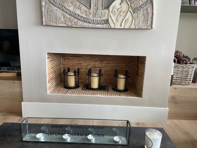 Una chimenea con tres velas y un cuadro encima.