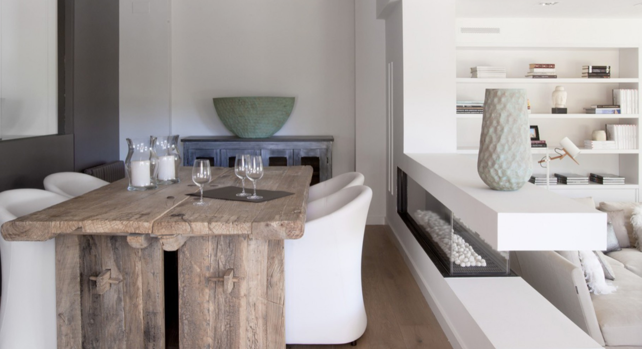 Un comedor con una mesa de madera y sillas blancas.