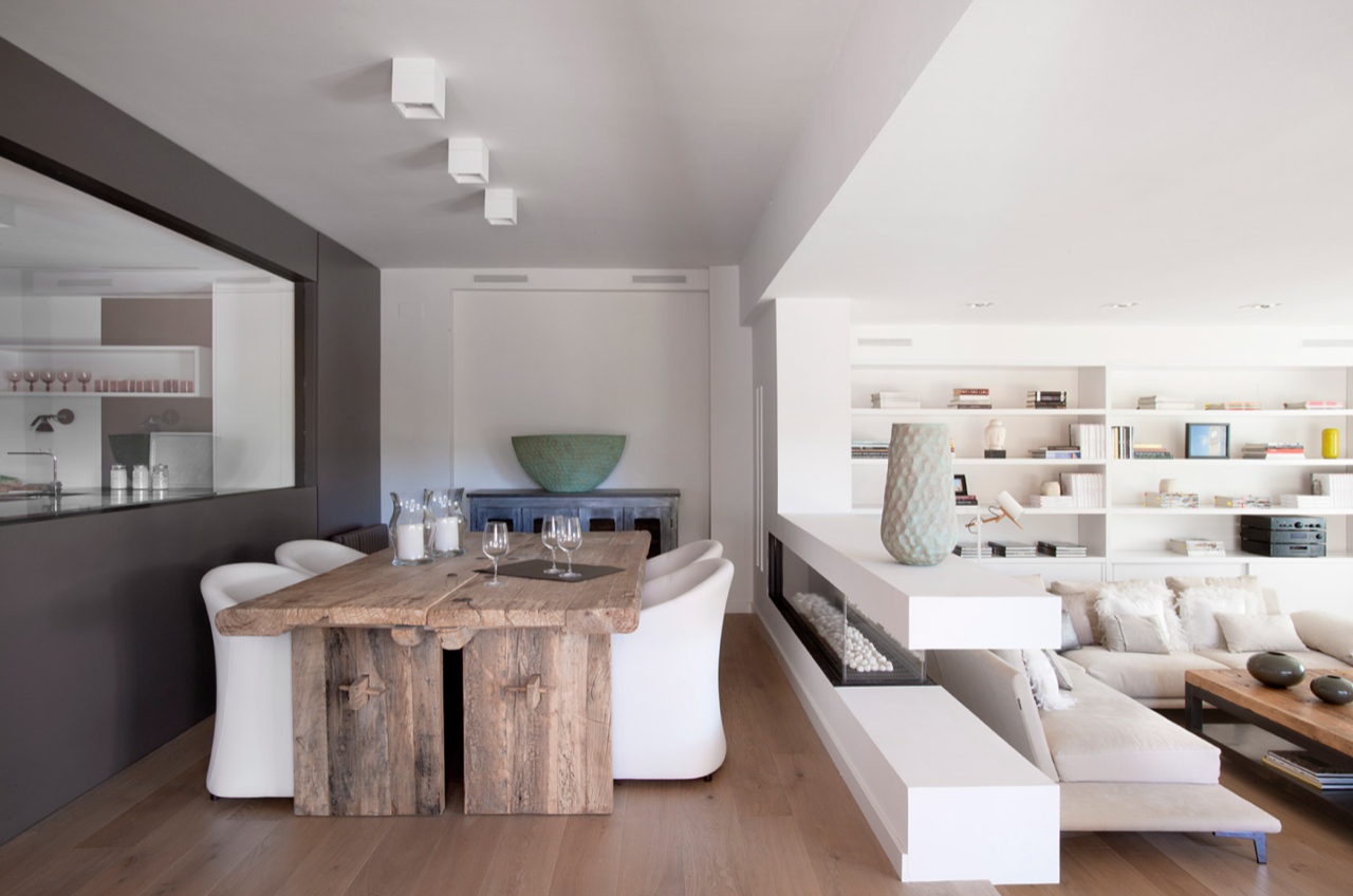 Un comedor con una mesa de madera y sillas blancas.