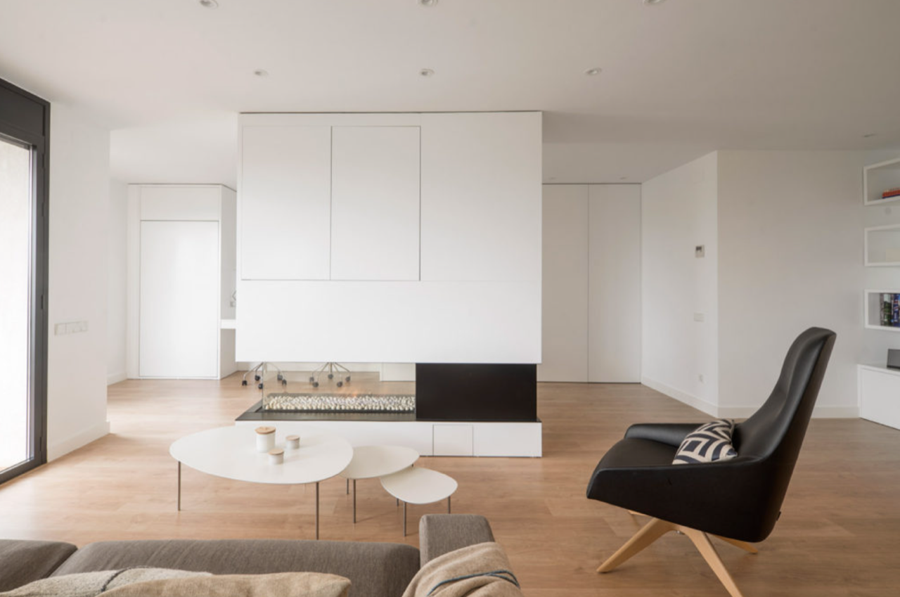 Una sala de estar con sofá, silla, mesa y chimenea.