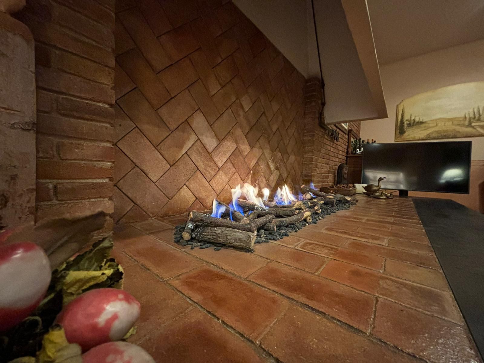 Una chimenea en una sala de estar con una pared de ladrillo y una televisión.