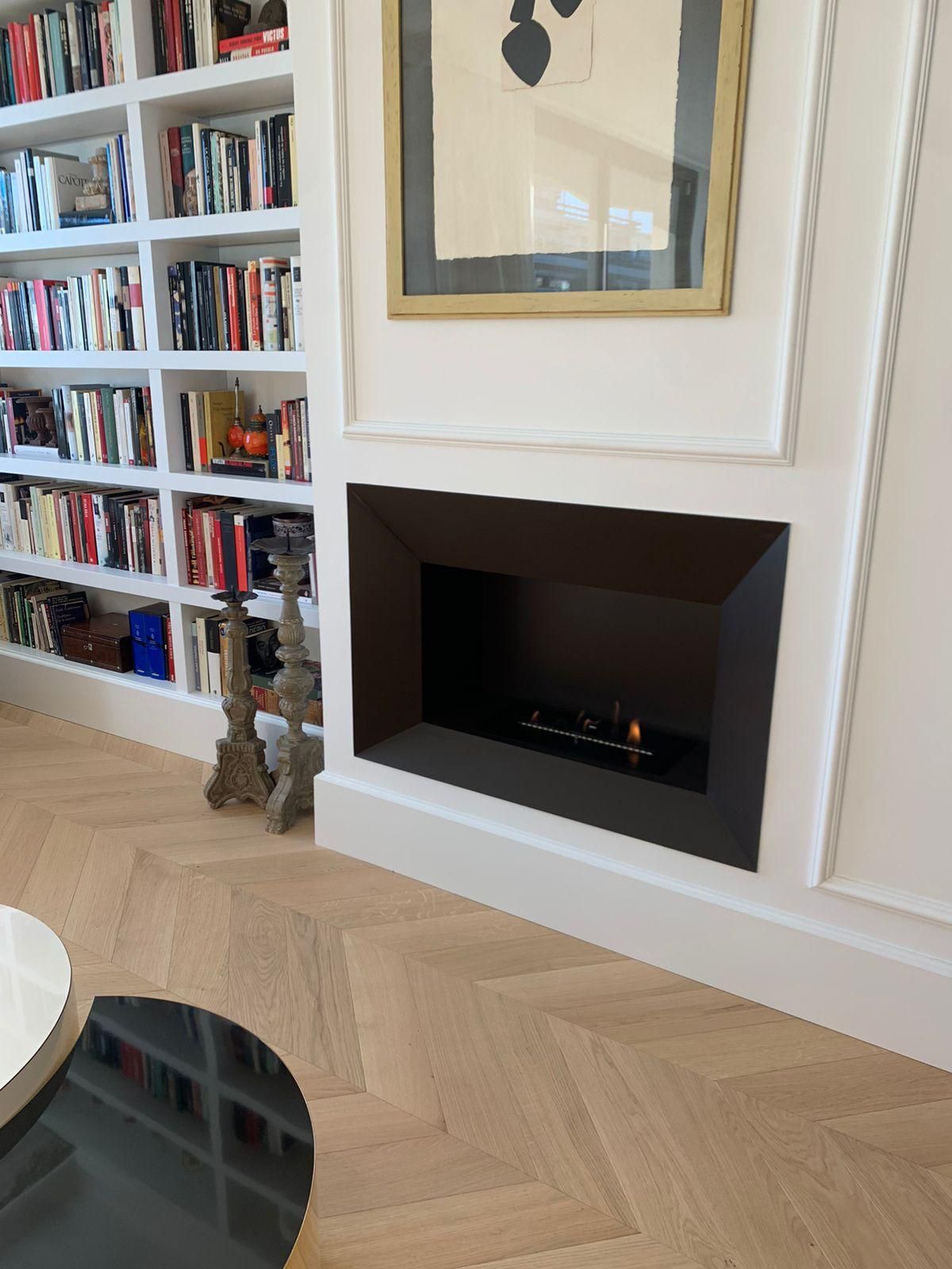 Una sala de estar con chimenea y estanterías.