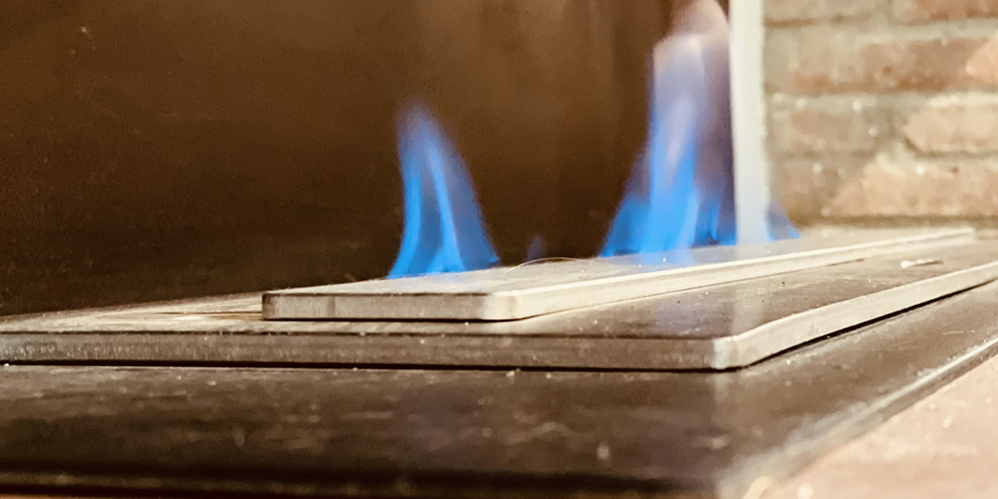 Un primer plano de una chimenea con llamas azules saliendo de ella.