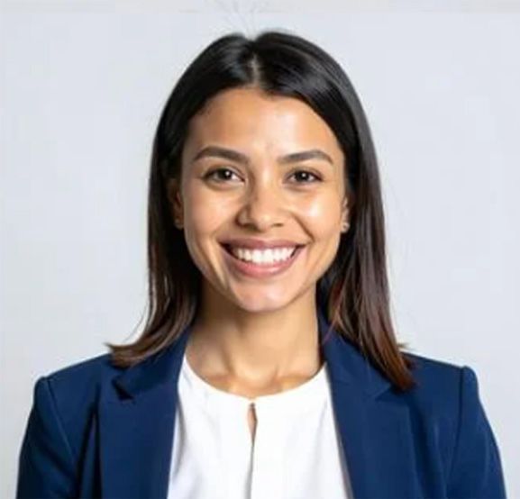 Woman with dark hair smiles, wearing a navy blazer over a white shirt, against a light gray background.