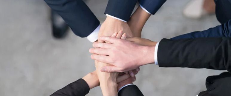 Hands of people in business suits stacked together.
