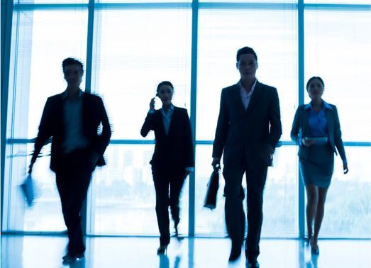 Four business people walking toward the camera in a modern building.