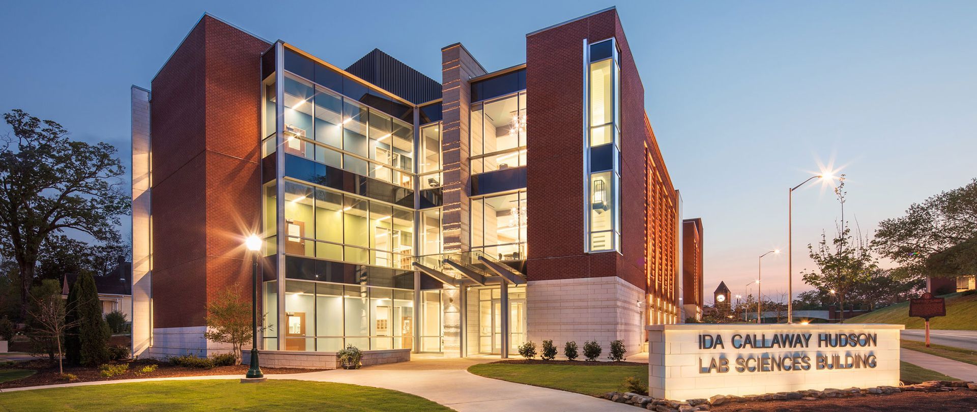 A large brick building with a lot of windows is lit up at night.