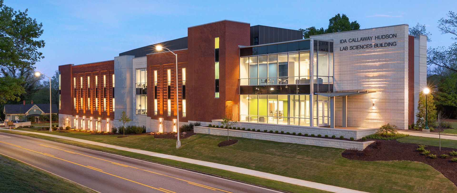 A large building with a lot of windows is sitting next to a road.