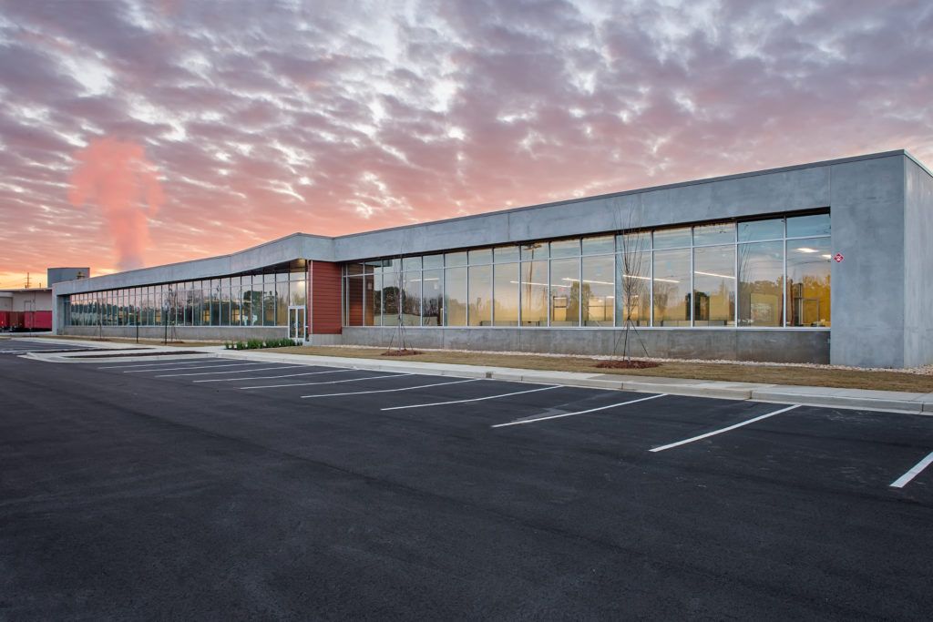 A large building with a lot of windows and a parking lot in front of it.