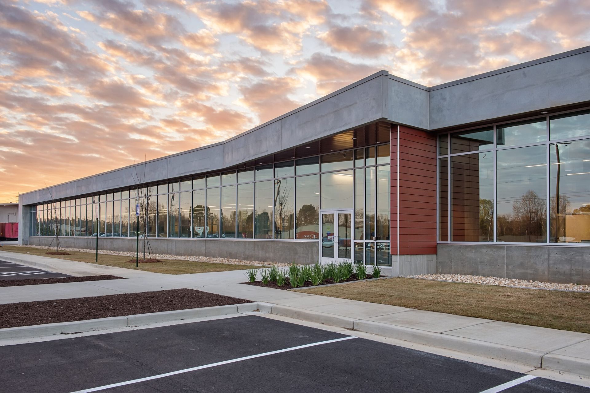 A large building with a lot of windows and a parking lot in front of it.
