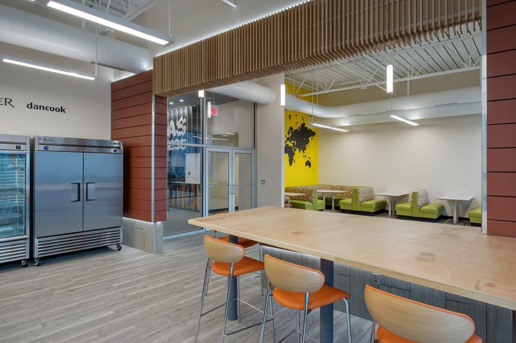 A room with a long table and chairs and a refrigerator.