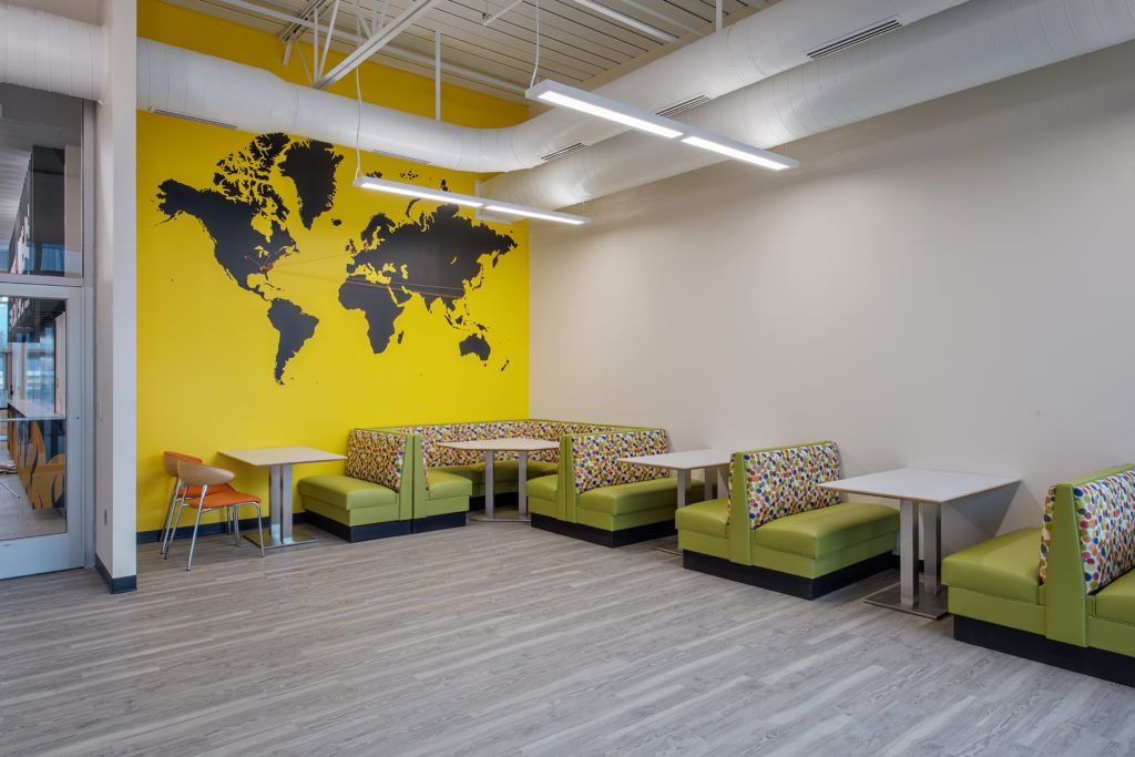 A room with tables and chairs and a map of the world on the wall.