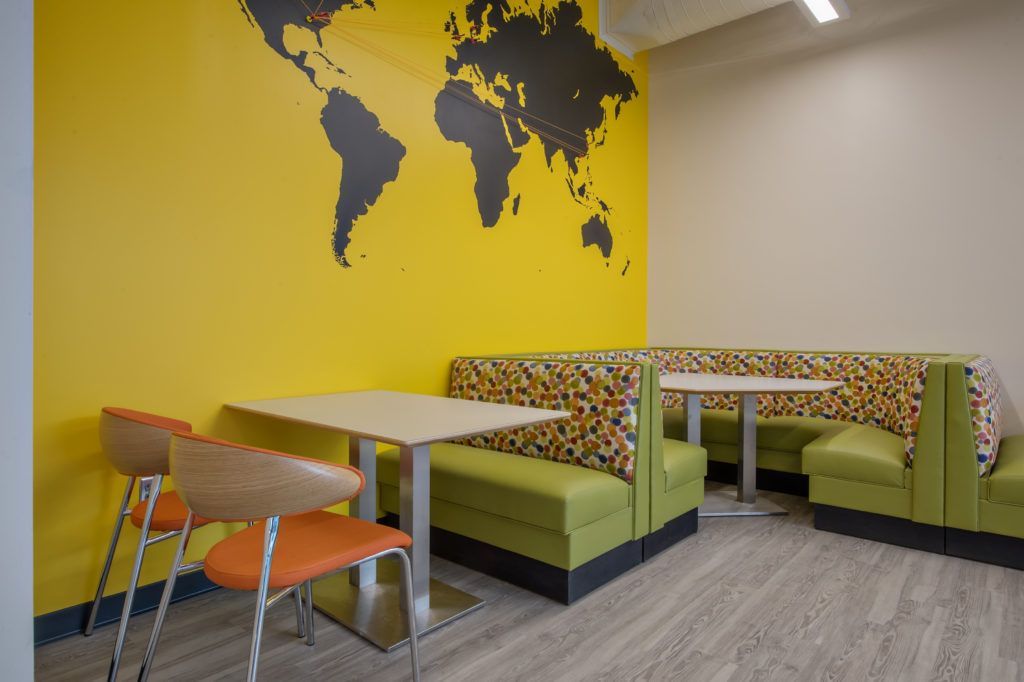 A room with tables and chairs and a map of the world on the wall.