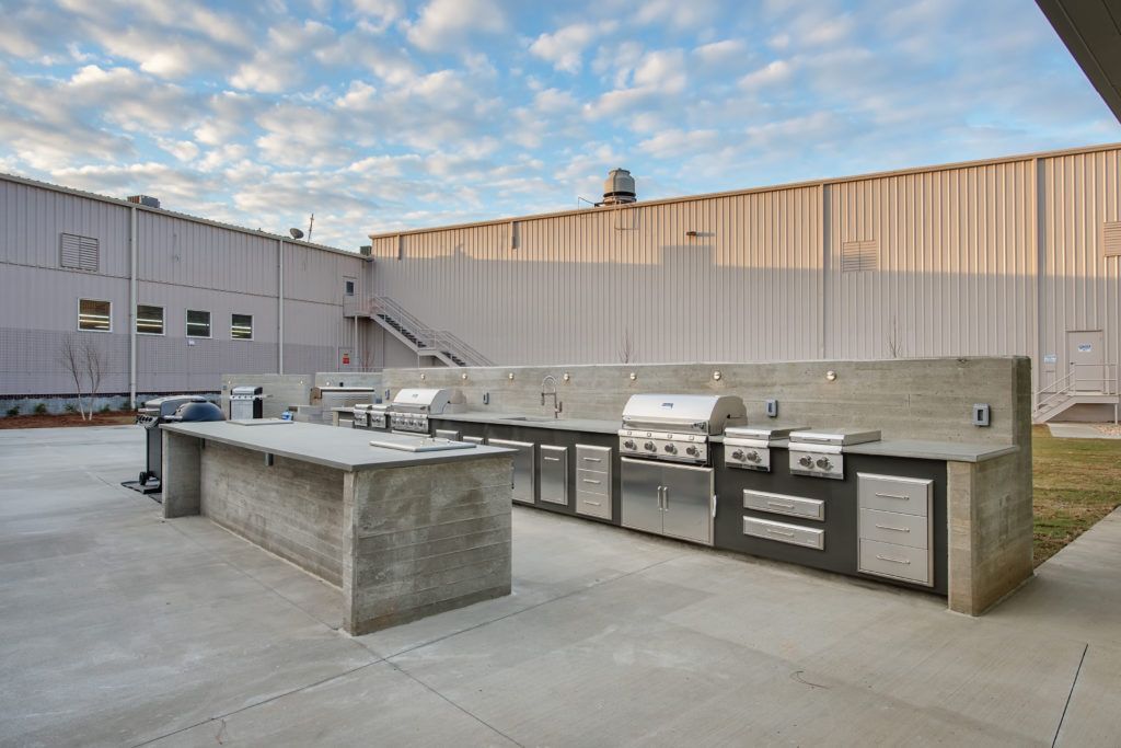 A large outdoor kitchen with stainless steel appliances and a large building in the background.
