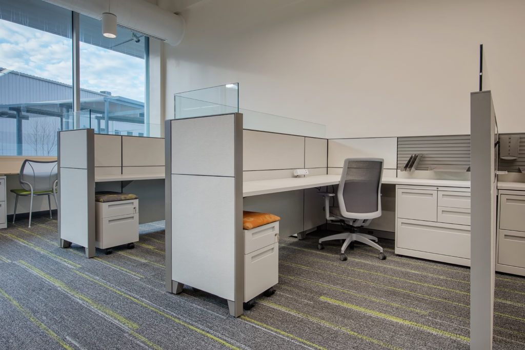 A cubicle in an office with a desk and chair.
