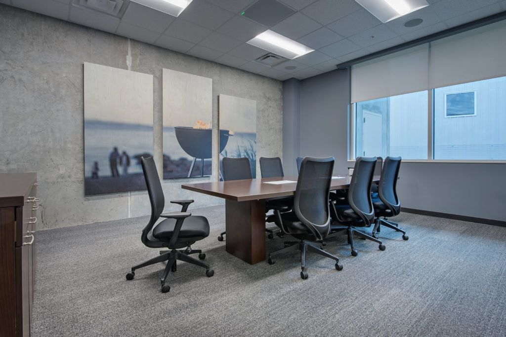 A conference room with a long table and chairs and paintings on the wall.