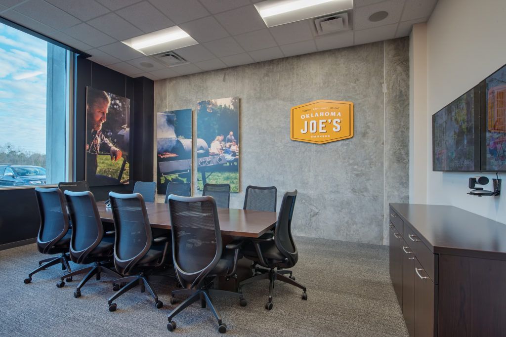 A conference room with a long table and chairs and a television.