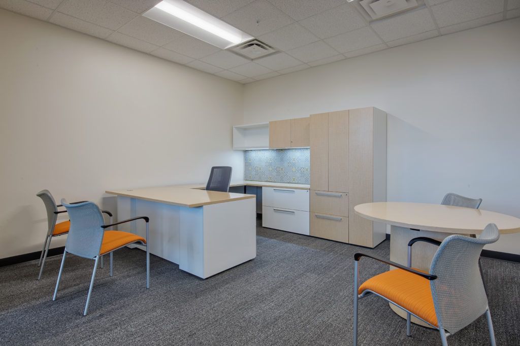 A small office with a desk , chairs , and a laptop.