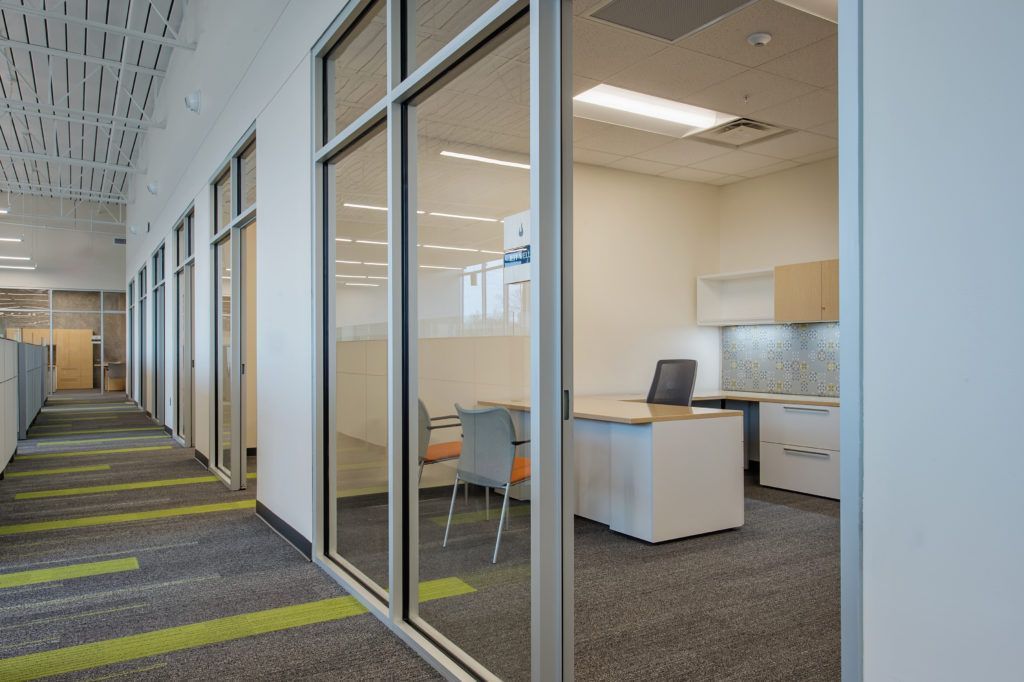 A hallway in an office building with a desk and chairs.
