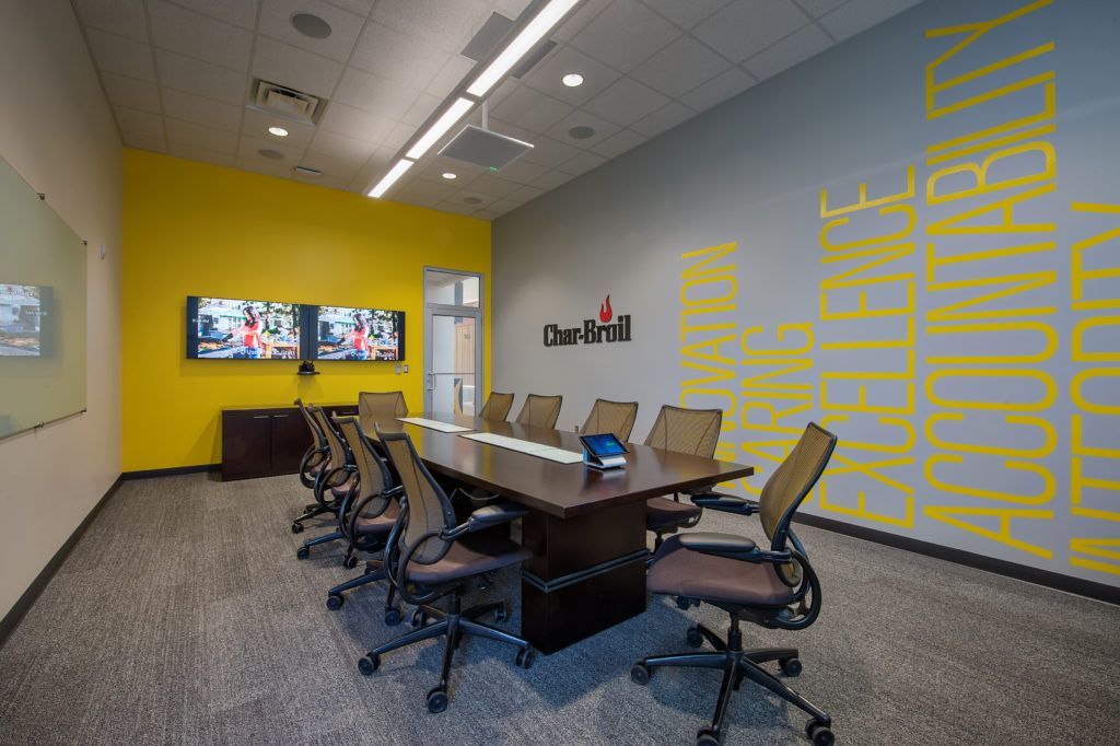 A conference room with a long table and chairs and yellow walls.