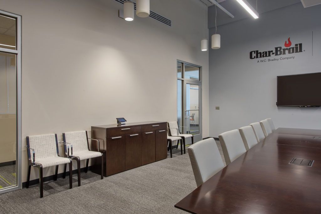 A conference room with a long table and chairs and a wall that says char grill