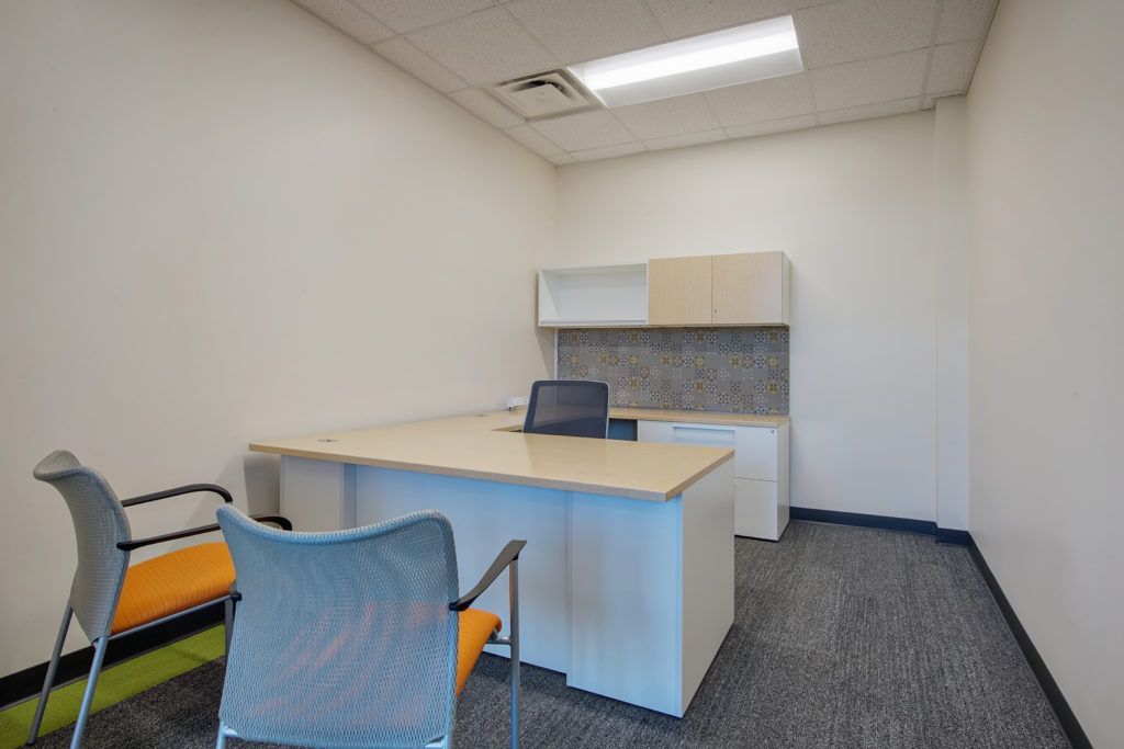 A small office with a desk and chairs in it.