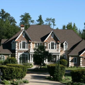 A large house with a brown roof is surrounded by trees