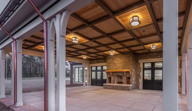 A large covered patio with a fireplace and a wooden ceiling.
