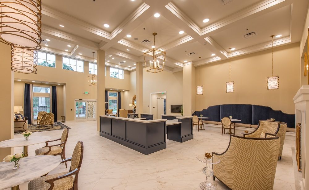 A large room with a reception desk , chairs , tables and a fireplace.