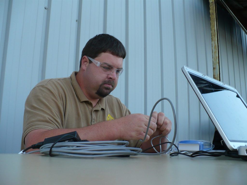 A man wearing safety glasses is working on a laptop