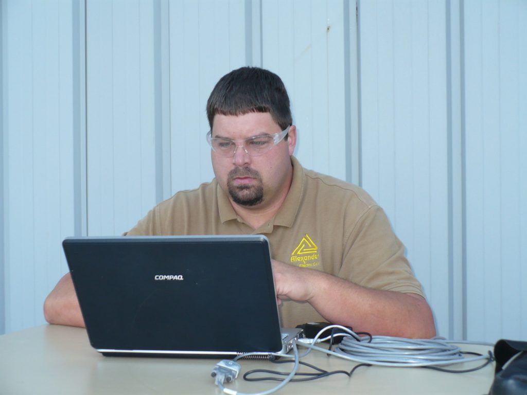 A man wearing glasses is using a lap top computer