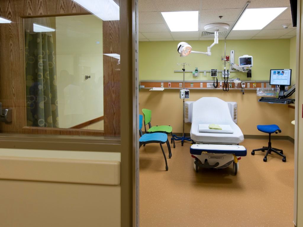 An empty hospital room with a bed and chairs