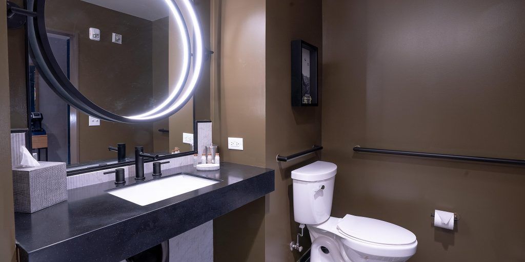 A bathroom with a toilet , sink and mirror.