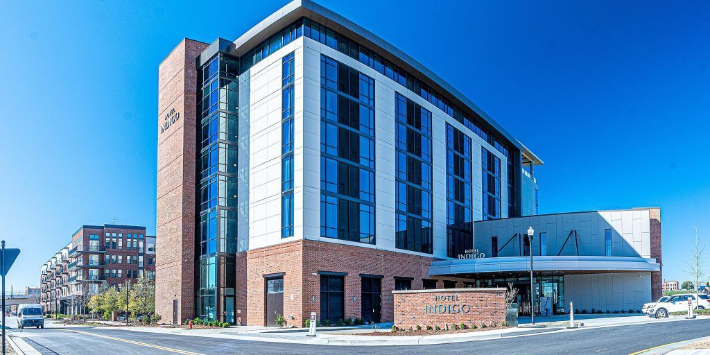 A large building with a lot of windows is sitting on the corner of a street.