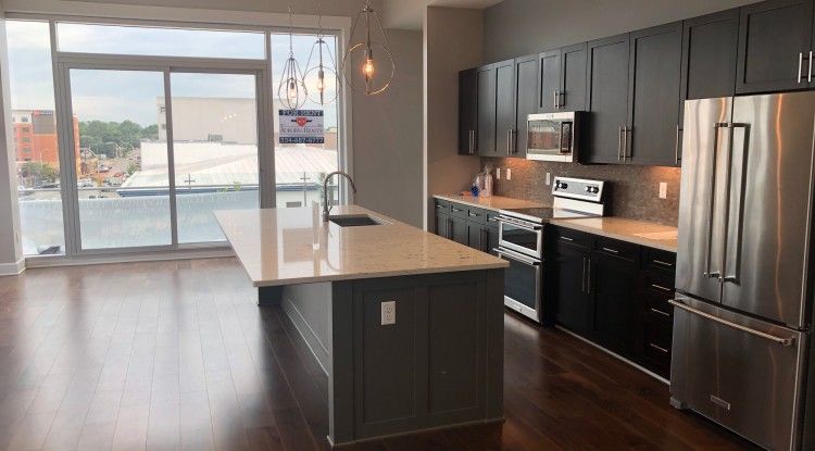 A kitchen with stainless steel appliances and a large island in the middle of the room.