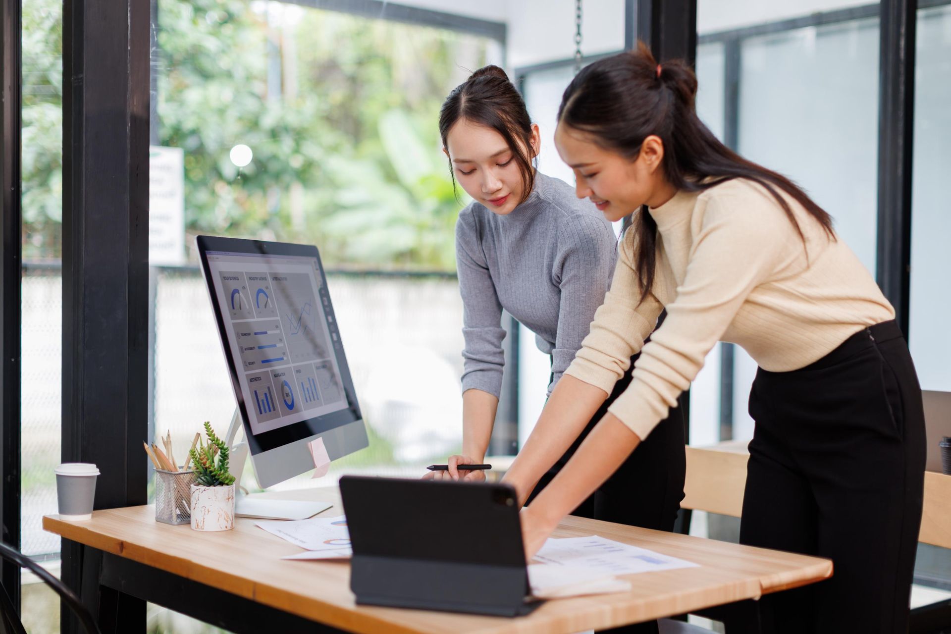 Two coworkers reviewing laptop data at a desk in a bright office