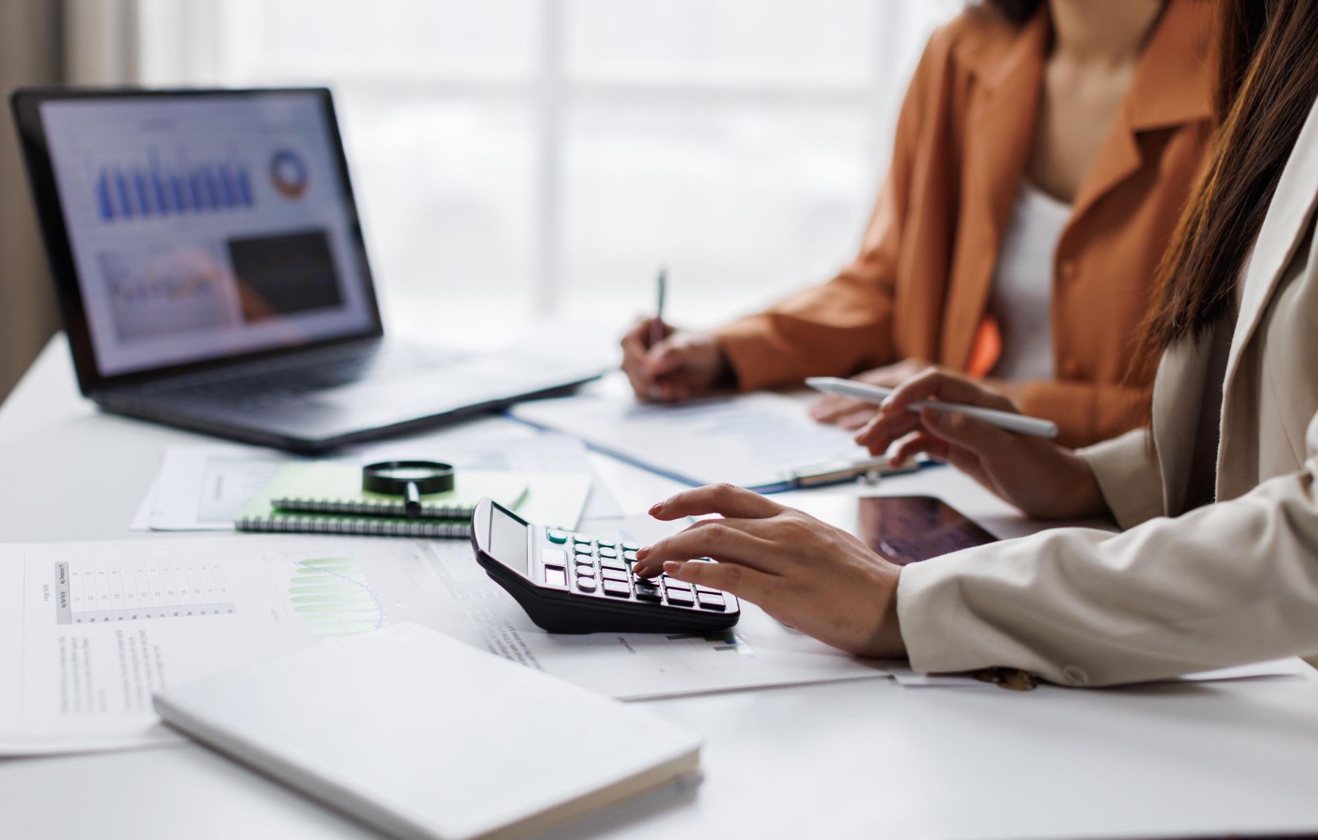 People reviewing financial documents at a desk with a laptop and calculator.