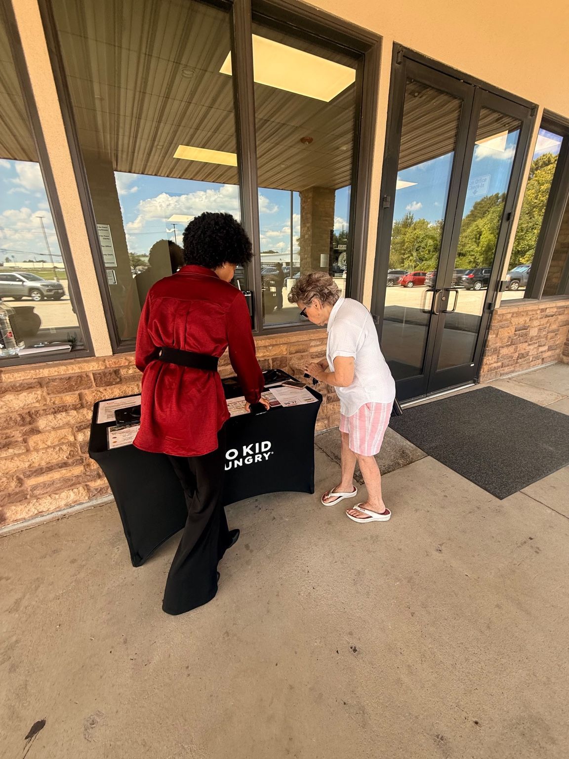 Uptown Connect representative speaking with a visitor at a No Kid Hungry outreach table